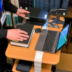 An RFID tagging technician works at a mobile workstation cart. Barcodes are scanned as a part of the tagging process.