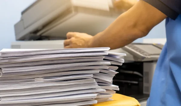 The papers stacked waiting to be copied with a copier machine.