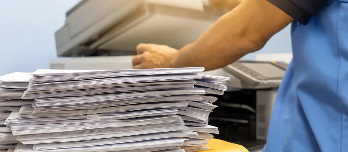 The papers stacked waiting to be copied with a copier machine.